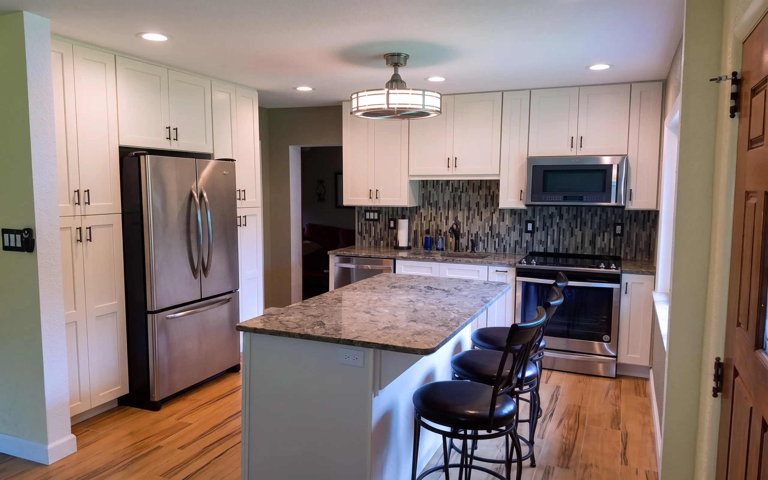 Remodeled kitchen with white shaker cabinets, stainless appliances, and a granite island.