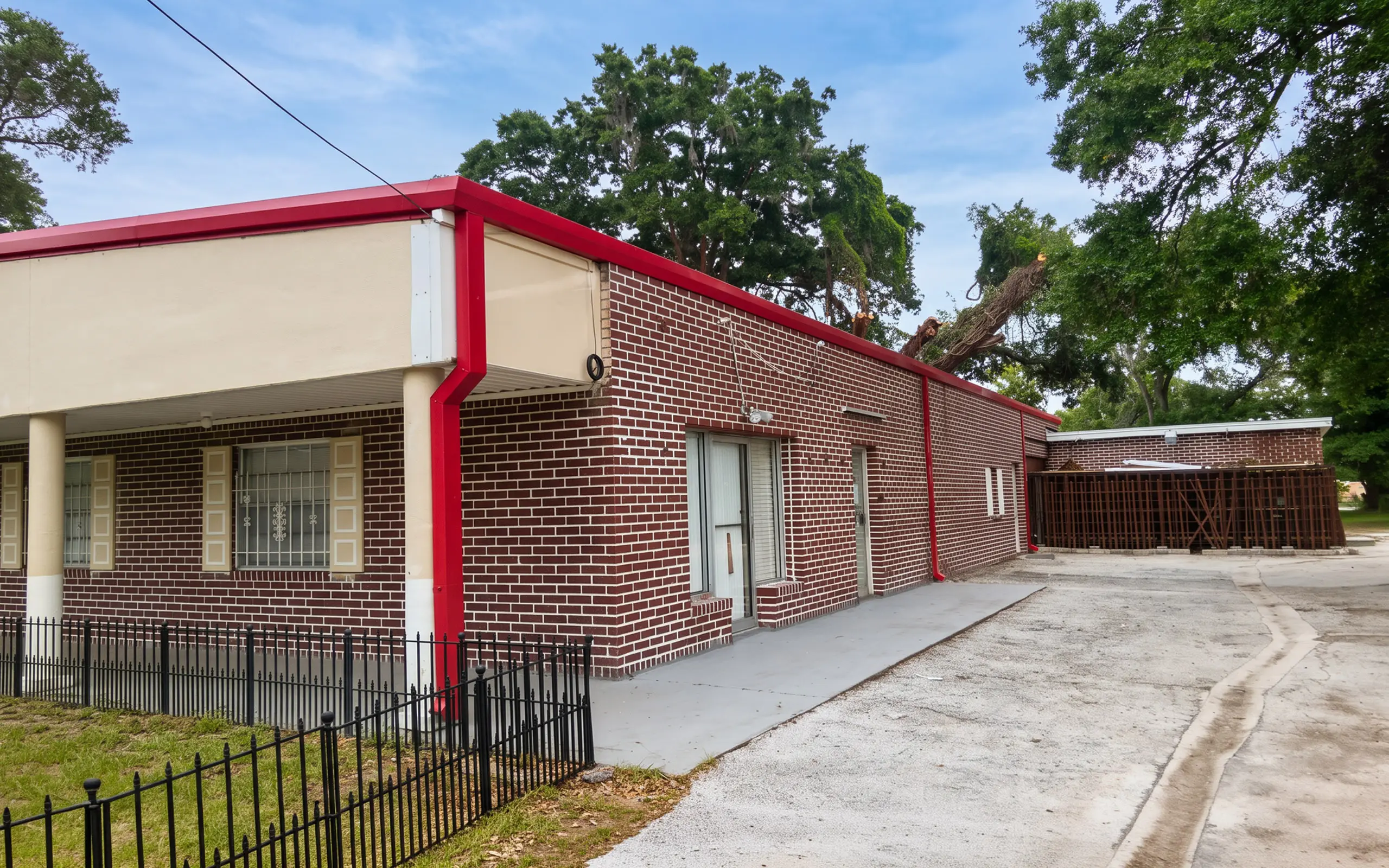 Red-brick commercial building with new red metal roofline trim and fascia.